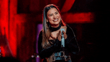 a woman is smiling while holding a microphone in front of her .