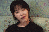 a woman in a black shirt is sitting on a couch with her mouth open