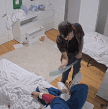 a man is standing next to another man laying on a bed