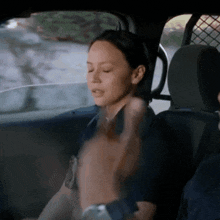 a woman is sitting in the back seat of a police car with her eyes closed