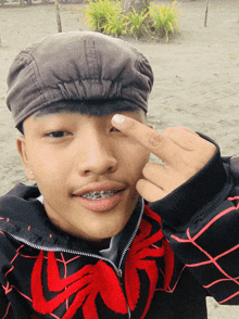a young man with braces on his teeth is wearing a black and red jacket with spiders on it