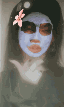 a woman with a mask on her face has a pink flower on her head