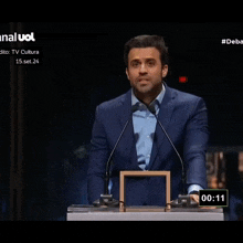 a man in a suit and tie is giving a speech in front of a microphone