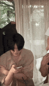 a man in a tan shirt with the word speed on it looks at his phone