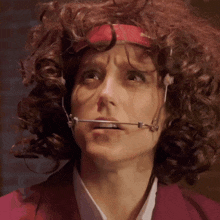 a woman with curly hair wearing a headband and braces