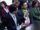 a man in a suit and tie is talking to another man in a crowd