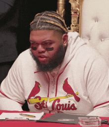 a man wearing a st. louis cardinals hoodie sits at a table