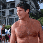 a shirtless man stands in front of a house