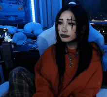 a woman wearing a red sweater and a cross necklace is sitting in a chair