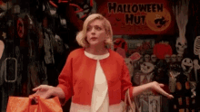 a woman in a red jacket is standing in front of a halloween sign .