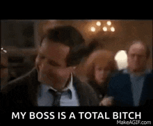 a man in a suit and tie is saying `` my boss is a total bitch '' in front of a crowd of people .