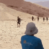 a group of people are walking on a dirt road .