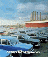 a bunch of blue cars are parked in front of a building that says o670entaxim debrecen