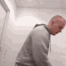 a man in a grey hoodie stands in a room