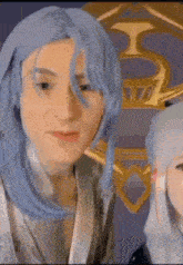 a man with blue hair is standing next to a woman in a costume .