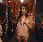 a woman in a pink top and shorts is holding a can