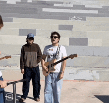 a man playing a guitar in front of a staircase with graffiti on it that says s.a.m.