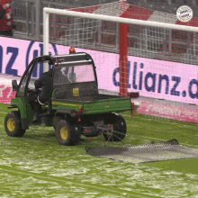 a john deere utility vehicle is on a soccer field in front of a sign that says allianz