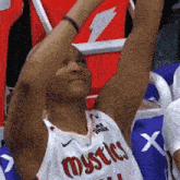 a basketball player wearing a mystics jersey holds up his arm