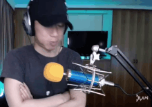 a man wearing headphones and a hat stands in front of a microphone with the letter n on the bottom
