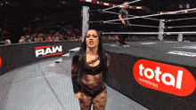 a woman stands in a wrestling ring with a total wireless sign in the background