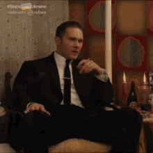 a man in a suit and tie is sitting in a chair smoking a cigar