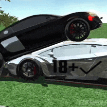 a black car is sitting on top of a white car in a grassy field .