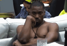 a shirtless man is sitting at a table with a woman behind him