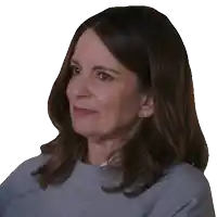 a woman wearing a grey sweater and earrings looks to the side
