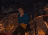 a woman in a blue shirt is standing in a dark room with her hands in the air .