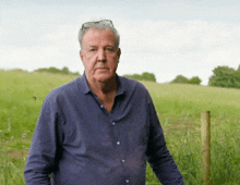 a man with glasses on his head stands in a field