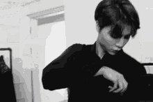 a black and white photo of a young man in a black shirt .