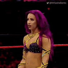 a female wrestler with purple hair is making a funny face while standing in a ring .