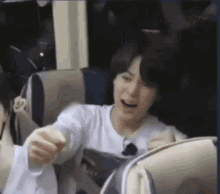 a man in a white shirt is sitting in a chair on a bus .
