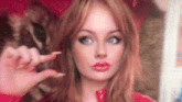 a woman with long red hair is making a funny face with her finger .