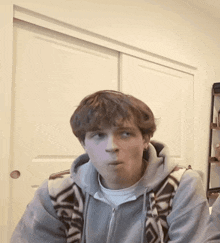 a young man wearing a grey hoodie with a pattern on the front