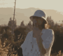 a woman wearing a white hat and a white shirt is smoking a cigarette .