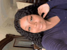 a woman in a blue shirt is taking a selfie in front of a mirror
