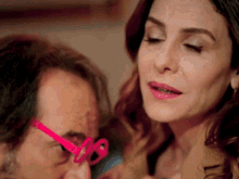 a woman wearing pink glasses is looking at a man