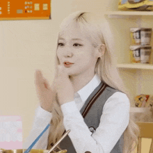 a girl in a school uniform is clapping her hands while sitting at a table .