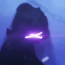 a purple light is shining on a person 's face in the dark