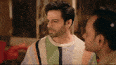 a man wearing a striped sweater is looking at another man