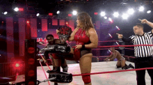 a woman in a red outfit is holding a trophy while a referee points at her