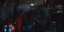 a large black dinosaur is standing in a dark room with a sign that says ' emergency ' on it