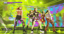 a group of girls are dancing on a stage with a colorful background .