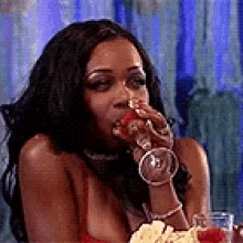 a woman is sitting at a table drinking from a glass .