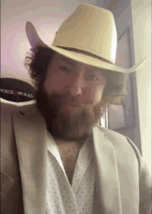 a man with a beard is wearing a cowboy hat