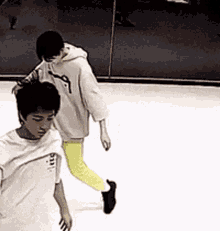 two young men are walking on a ice rink and one of them is wearing a white shirt that says ' i love you '