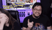 a man giving a thumbs up in front of a woman who is covering her face with her hand