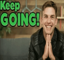 a man in a leather jacket is smiling in front of a sign that says " keep going "